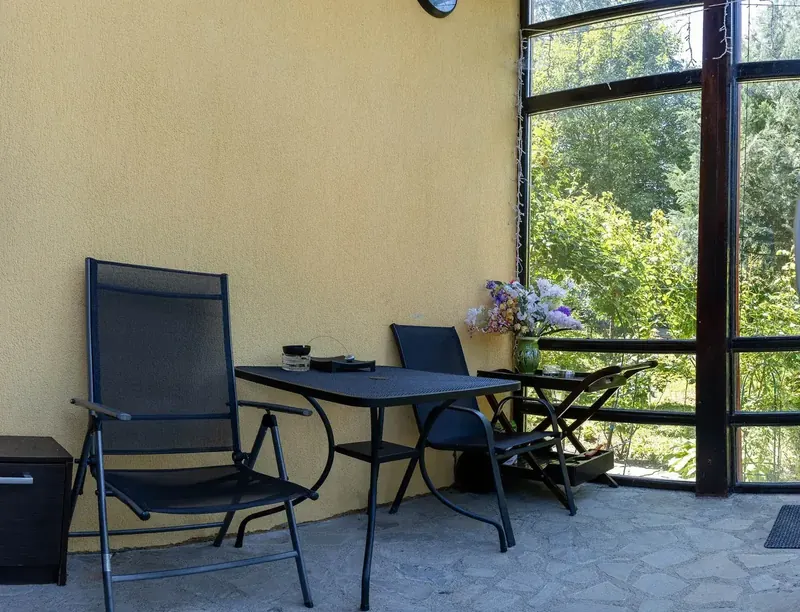Terasa închisă a Casei Primăverii, cu masă și vedere spre grădină